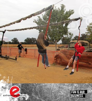 Corporate family fun days children having fun on a zip line over a sand covered are