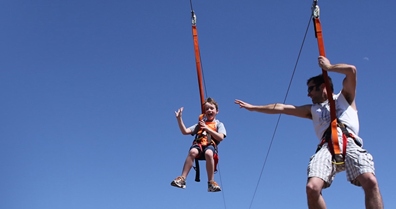 Fun corporate event showing man and young man zip lining down a wire