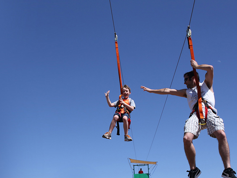Fun corporate event showing man and young man zip lining down a wire